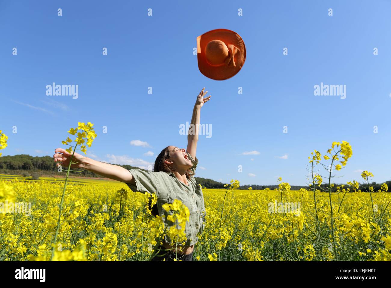 Happy woman throwing pamela celebrating vacation in a yellow flowered field in spring Stock Photo