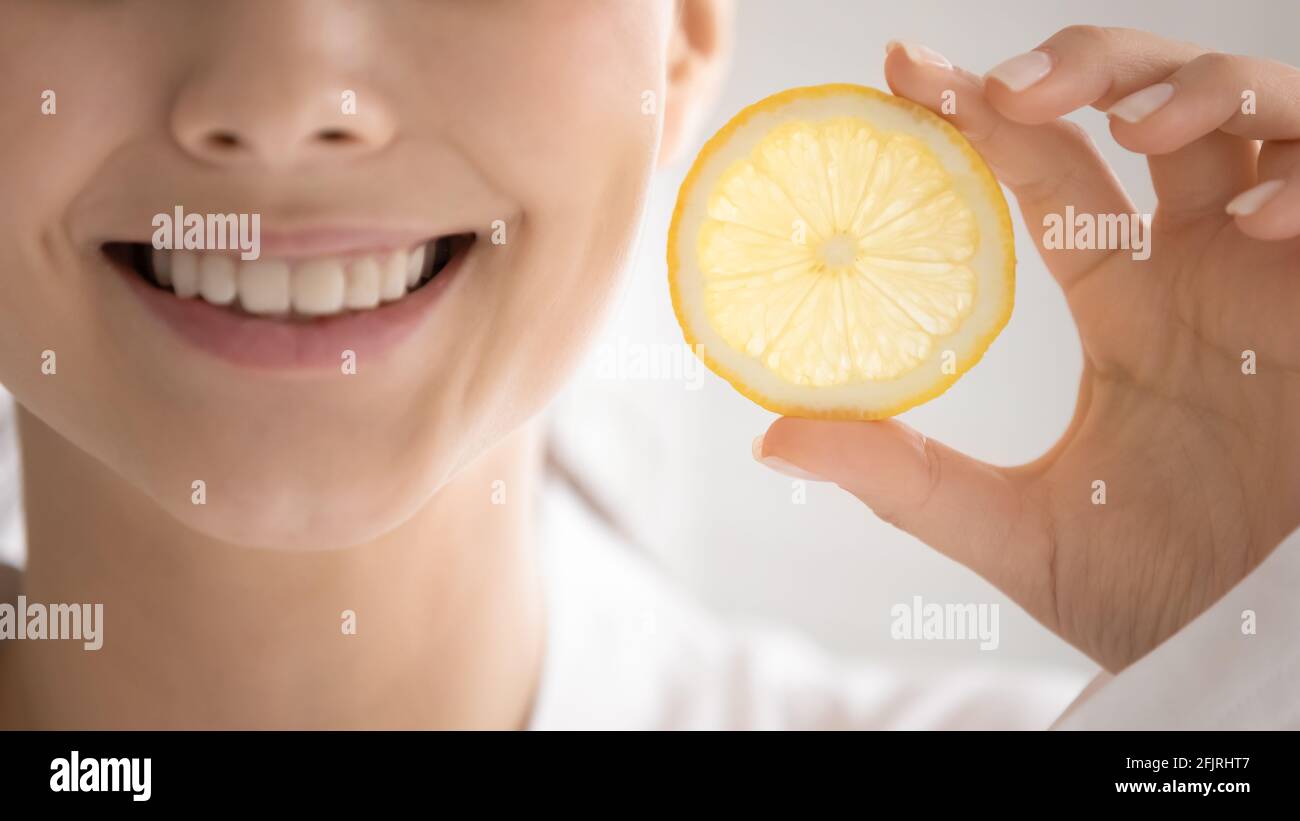 Toothy smile of happy young woman showing slice of lemon Stock Photo ...
