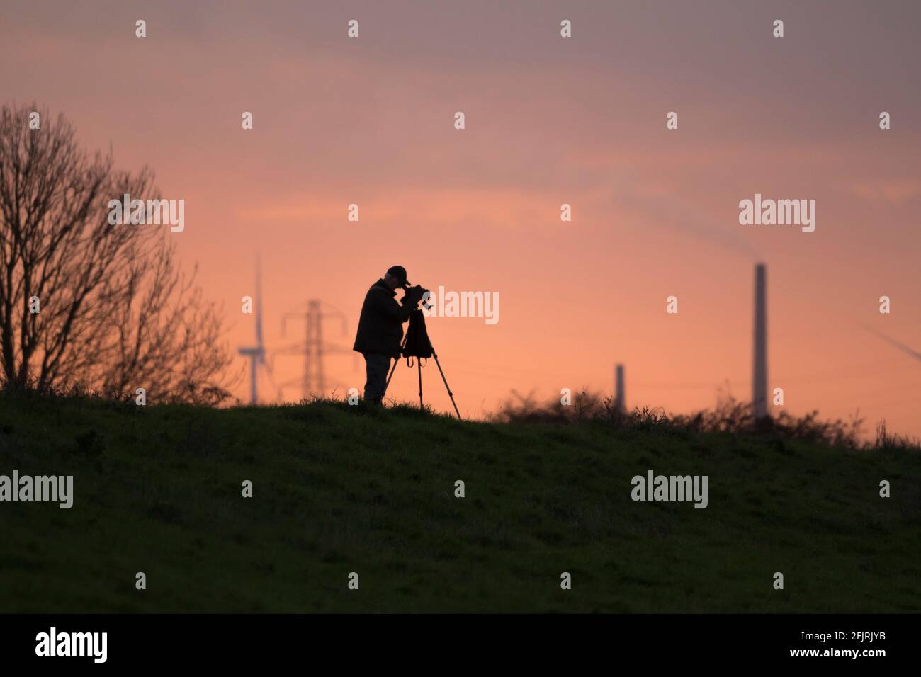 Silhouetted birdwatcher looking through spotting scope Stock Photo