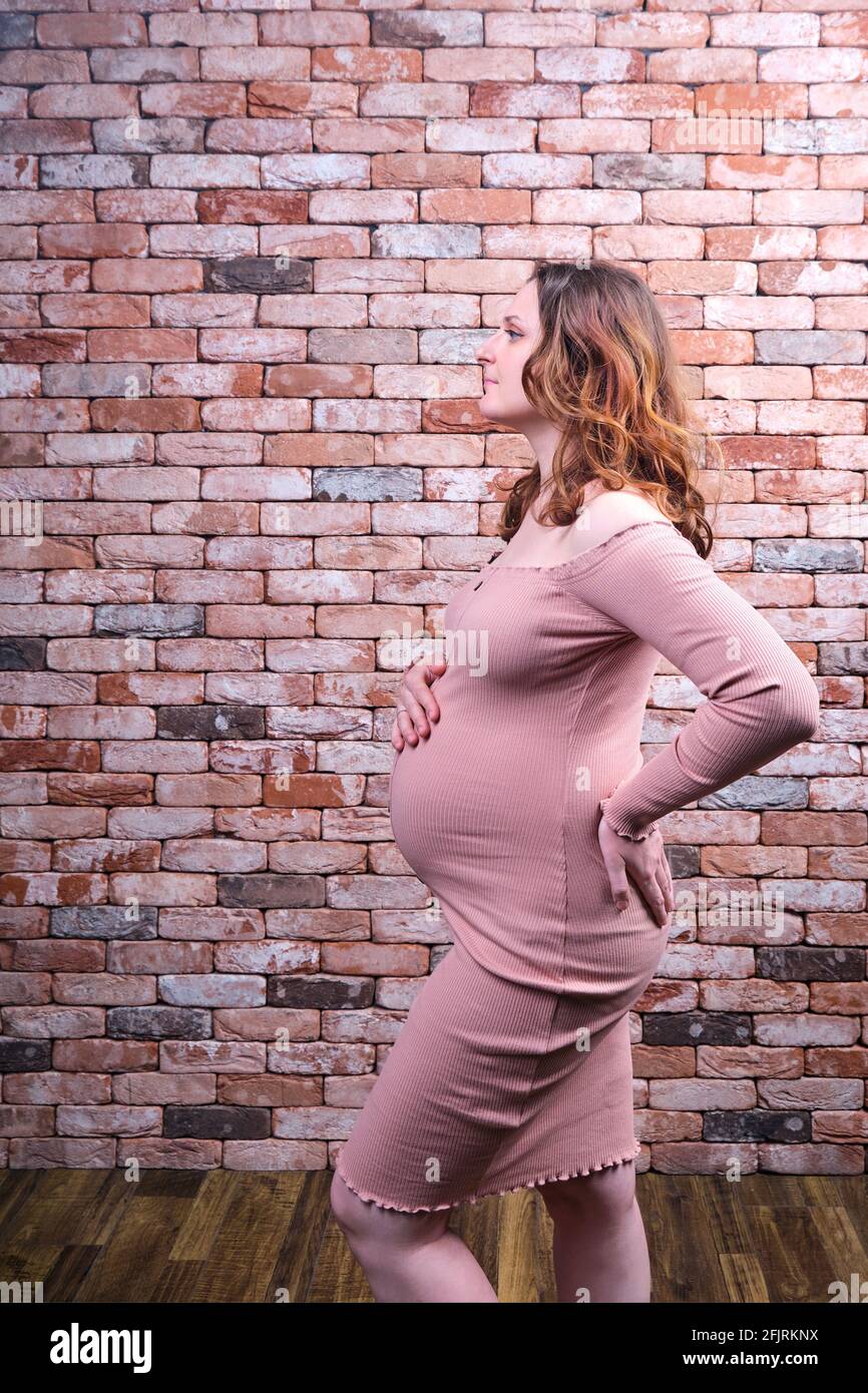 Portrait of a happy pregnant woman against the background of a red brick  wall. Smiling adult woman with pregnant belly in red tight dress Stock  Photo - Alamy