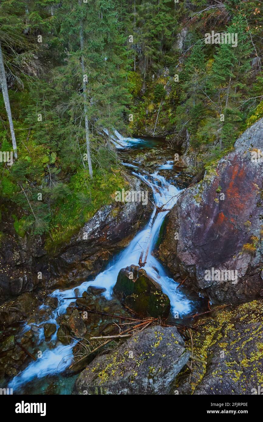 A rushing stream flowing through the mountains and cascading down Stock Photo