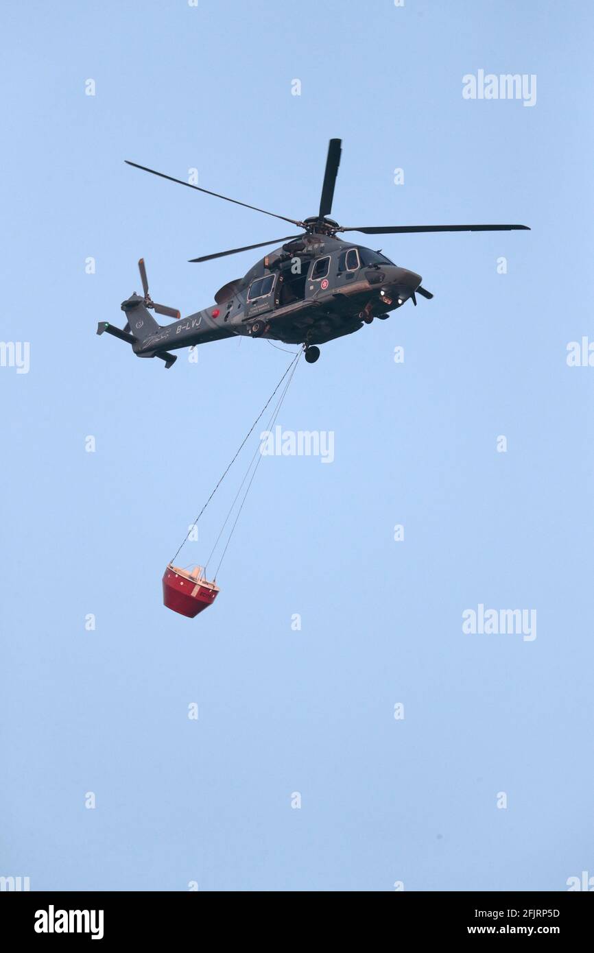 Vertical composition, Hong Kong Government Flying Services, Super Puma helicopter, in flight, a fire bucket hanging below, Hong Kong 28th April 2021 Stock Photo