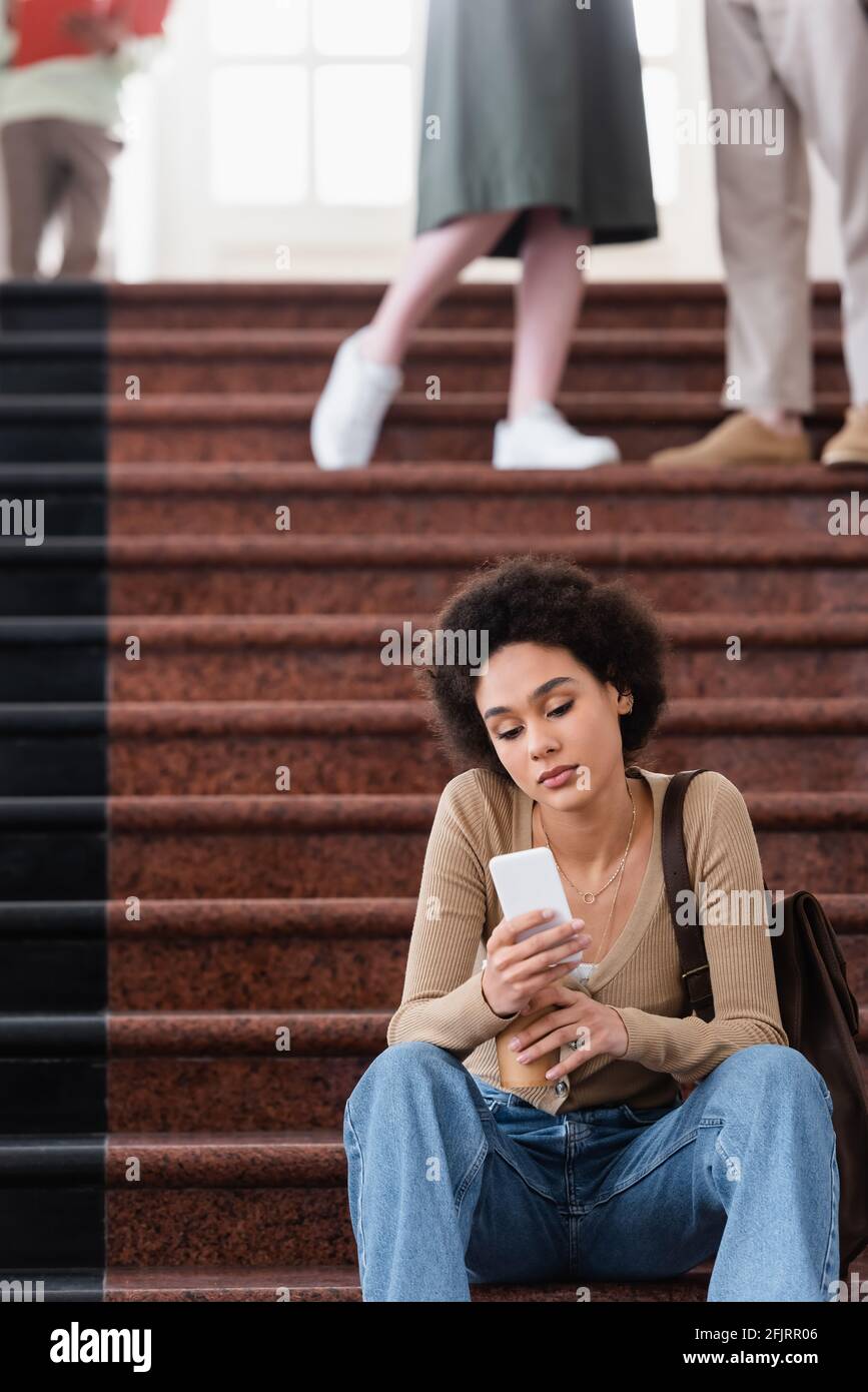 African american student using cellphone on stairs in university Stock ...