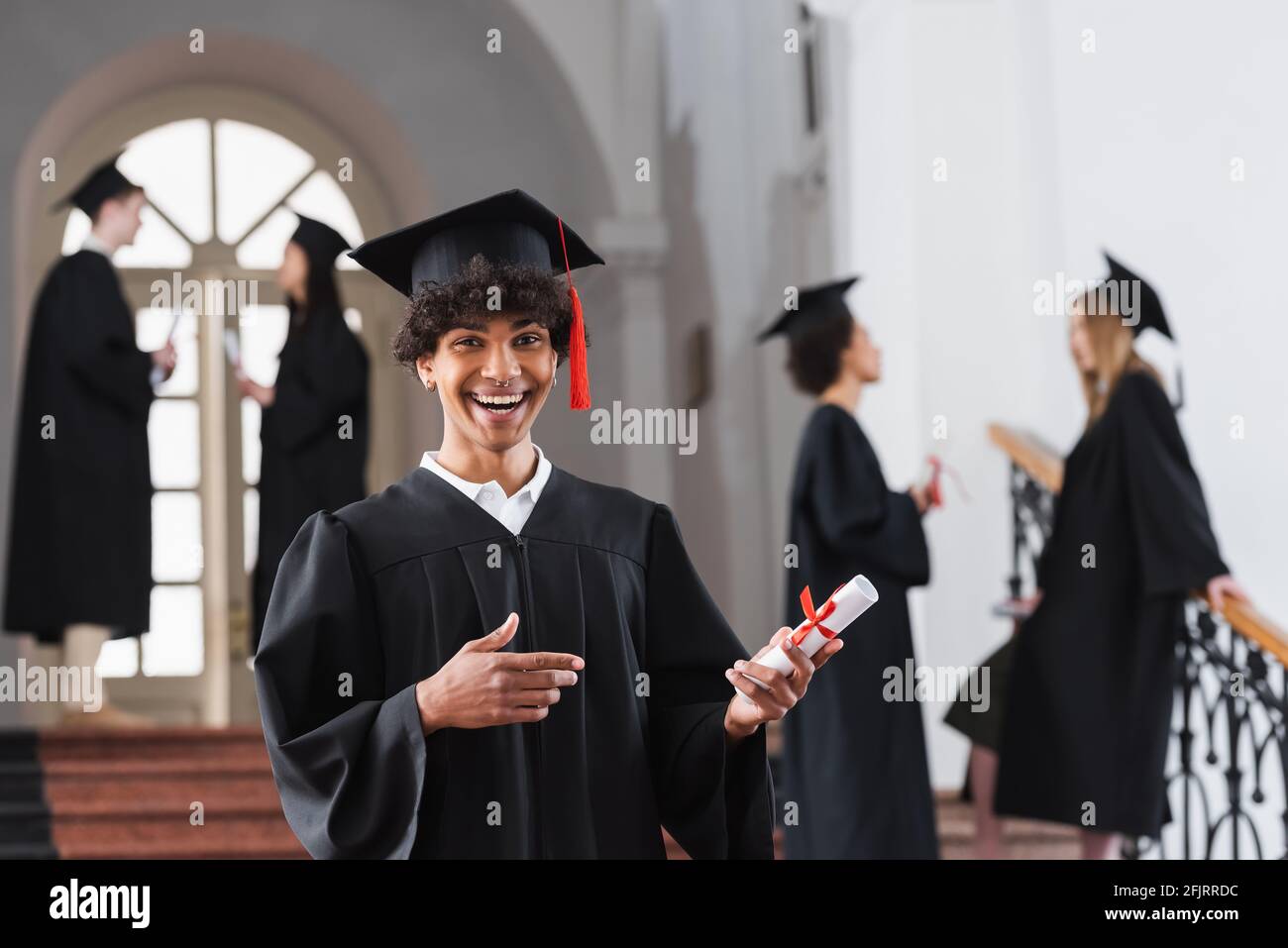 Excited african american bachelor pointing at diploma Stock Photo - Alamy