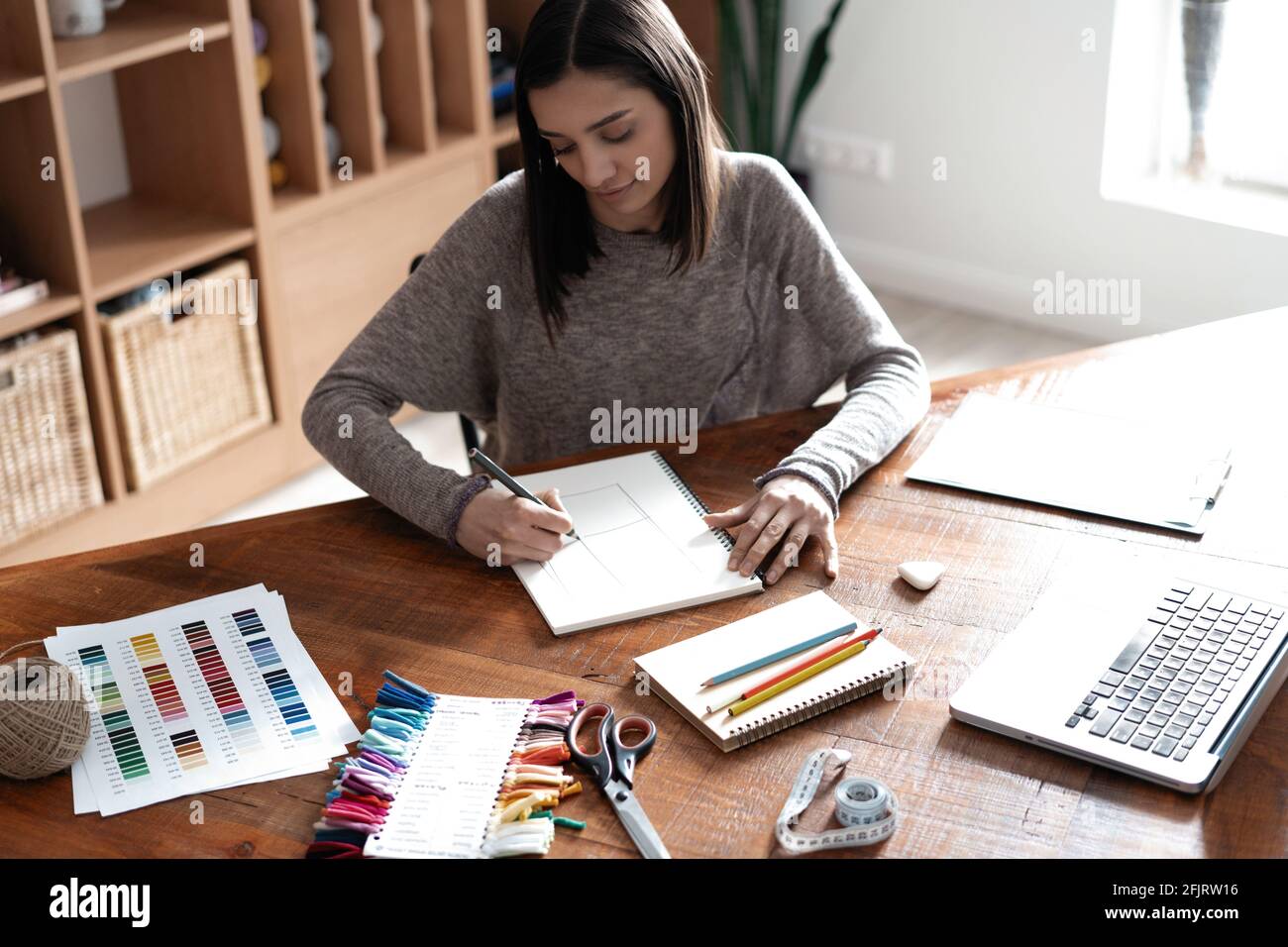 Indian mixed-race pretty designer working at her desk in her office. Stock Photo