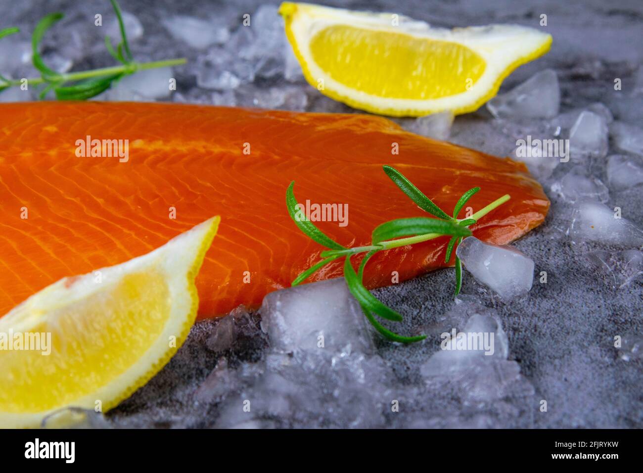 Fresh raw salmon fish steak with spices on ice over dark stone ...