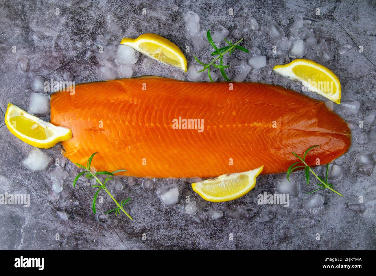 Fresh raw salmon fish steak with spices on ice over dark stone ...
