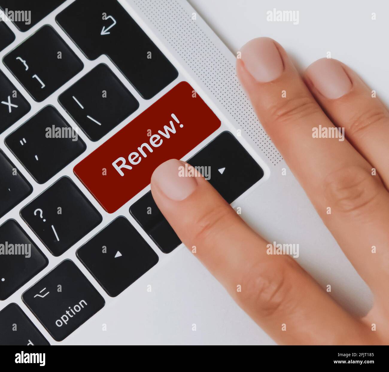 Person's fingers about to press 'Renew!' key on a black laptop keyboard on an office desk. Click to renew. Stock Photo