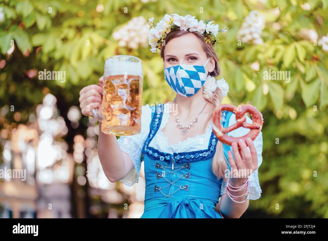 Bavarian woman toasting with beer during covid 19 Stock Photo