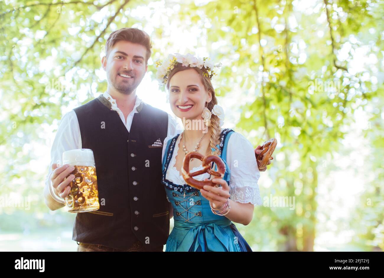 Bavarian couple in Tracht toasting with beer Stock Photo
