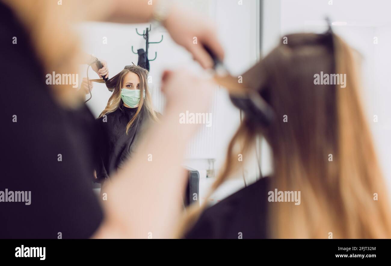 Hair stylist and customer during coronavirus pandemic wearing mask Stock Photo
