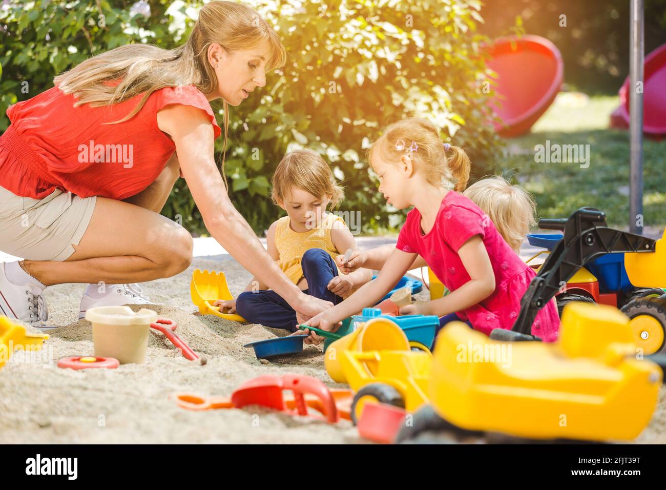 Children and play school teacher enjoying some time in sand box Stock Photo