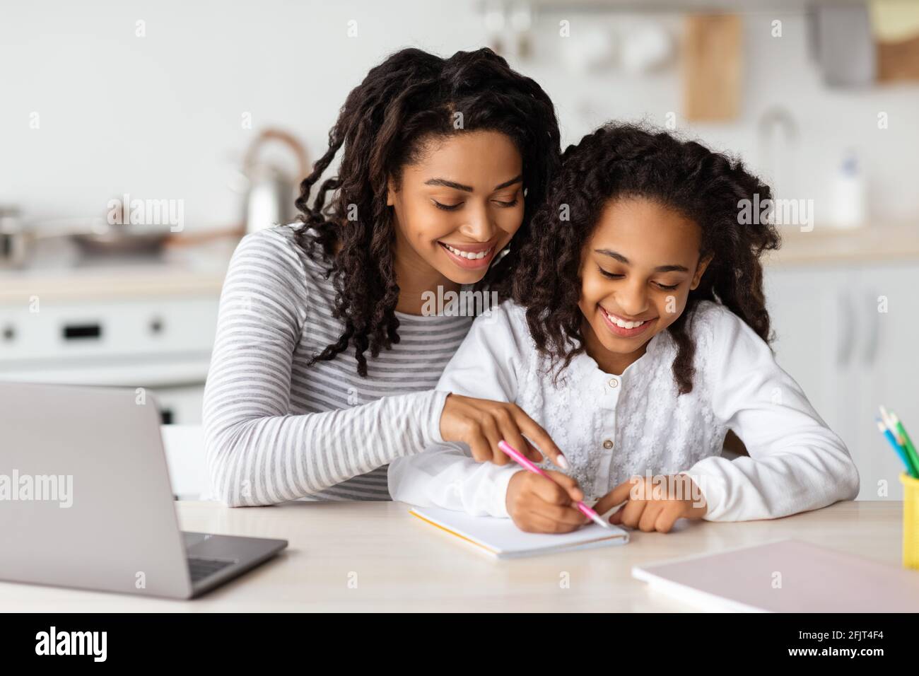 Beautiful black mother helping her daughter with homework Stock Photo ...