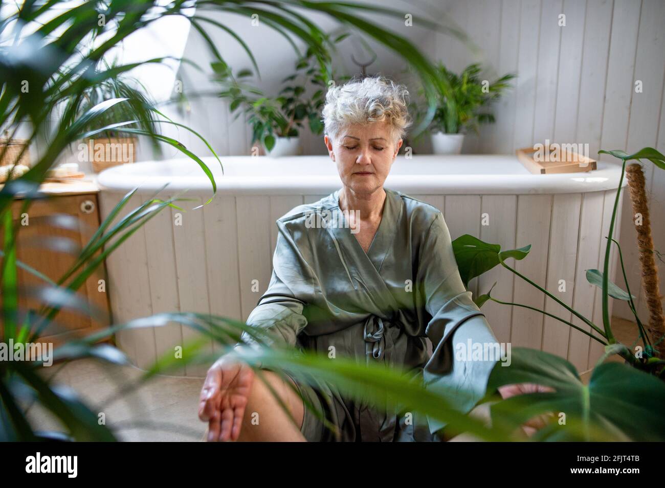 Senior woman doing yoga in bathroom at home, relax and self-care concept. Stock Photo