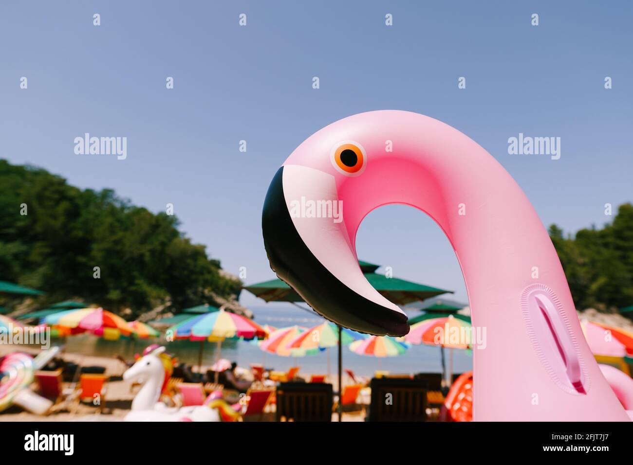 Inflatable pink flamingo on the royal beach in Przno against the background of green trees Stock Photo
