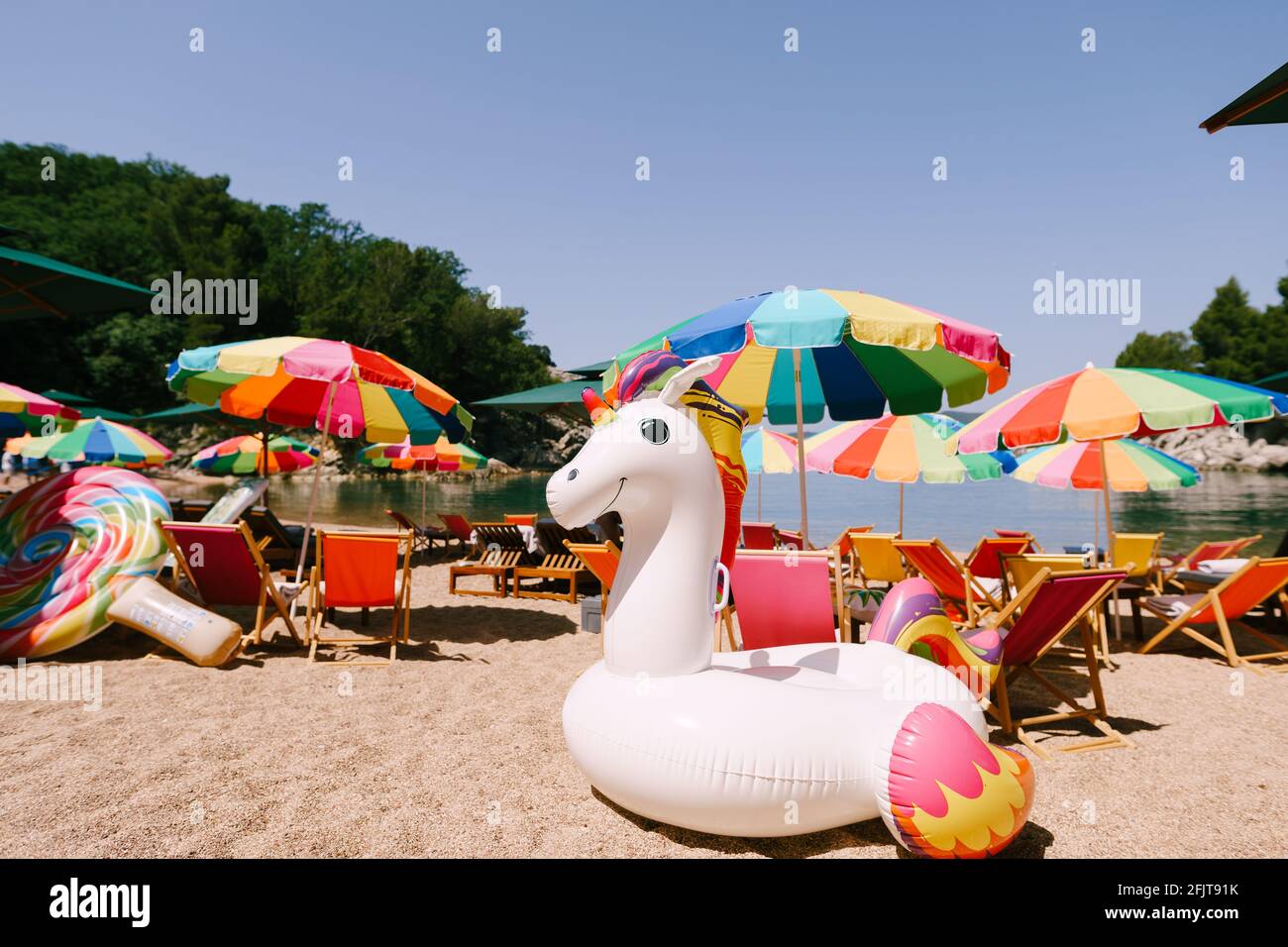 Inflatable white unicorn on the royal beach in Przno against the backdrop of green trees Stock Photo