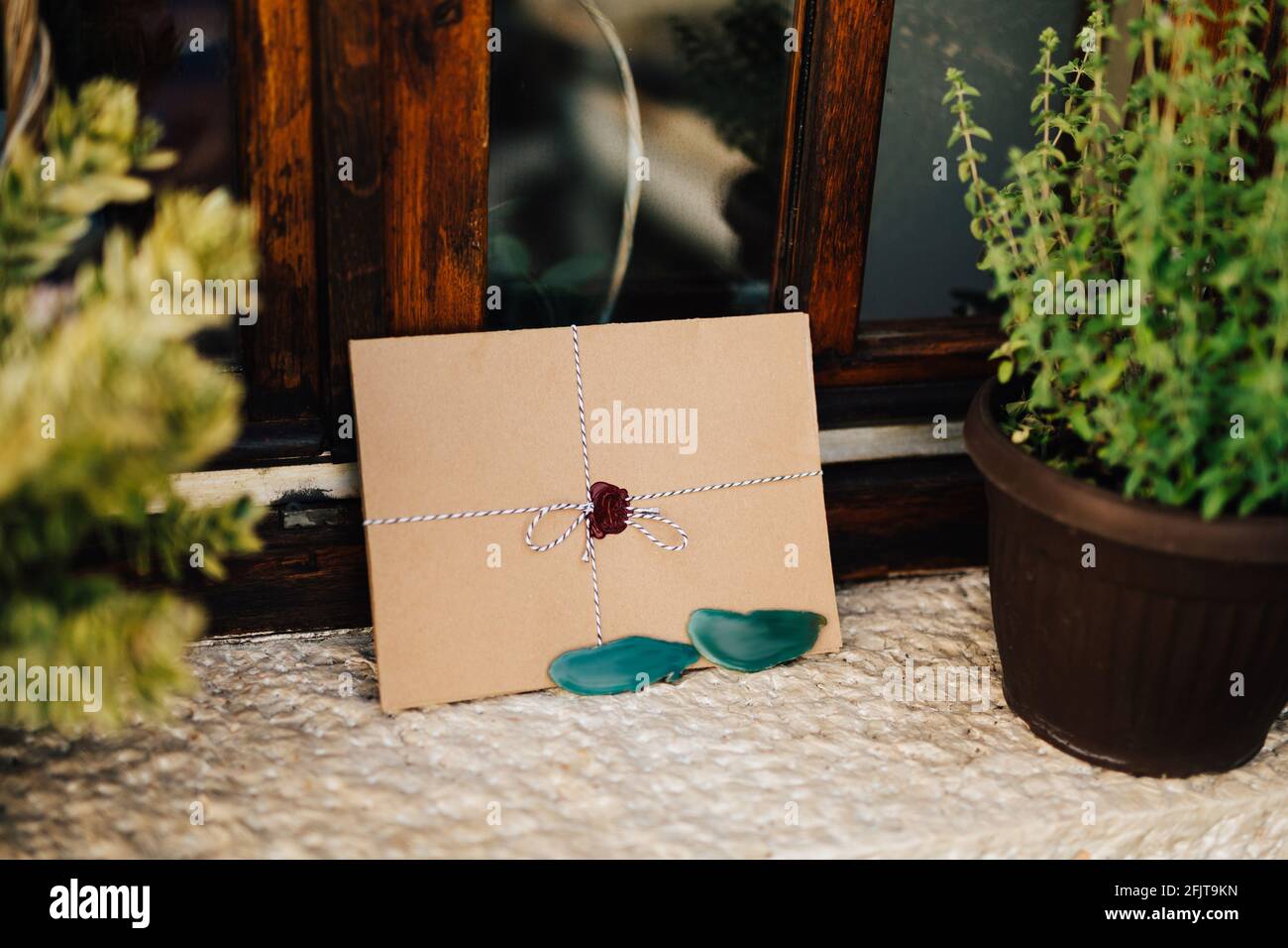 Brown envelope tied with a colorful string is on the white windowsill ...