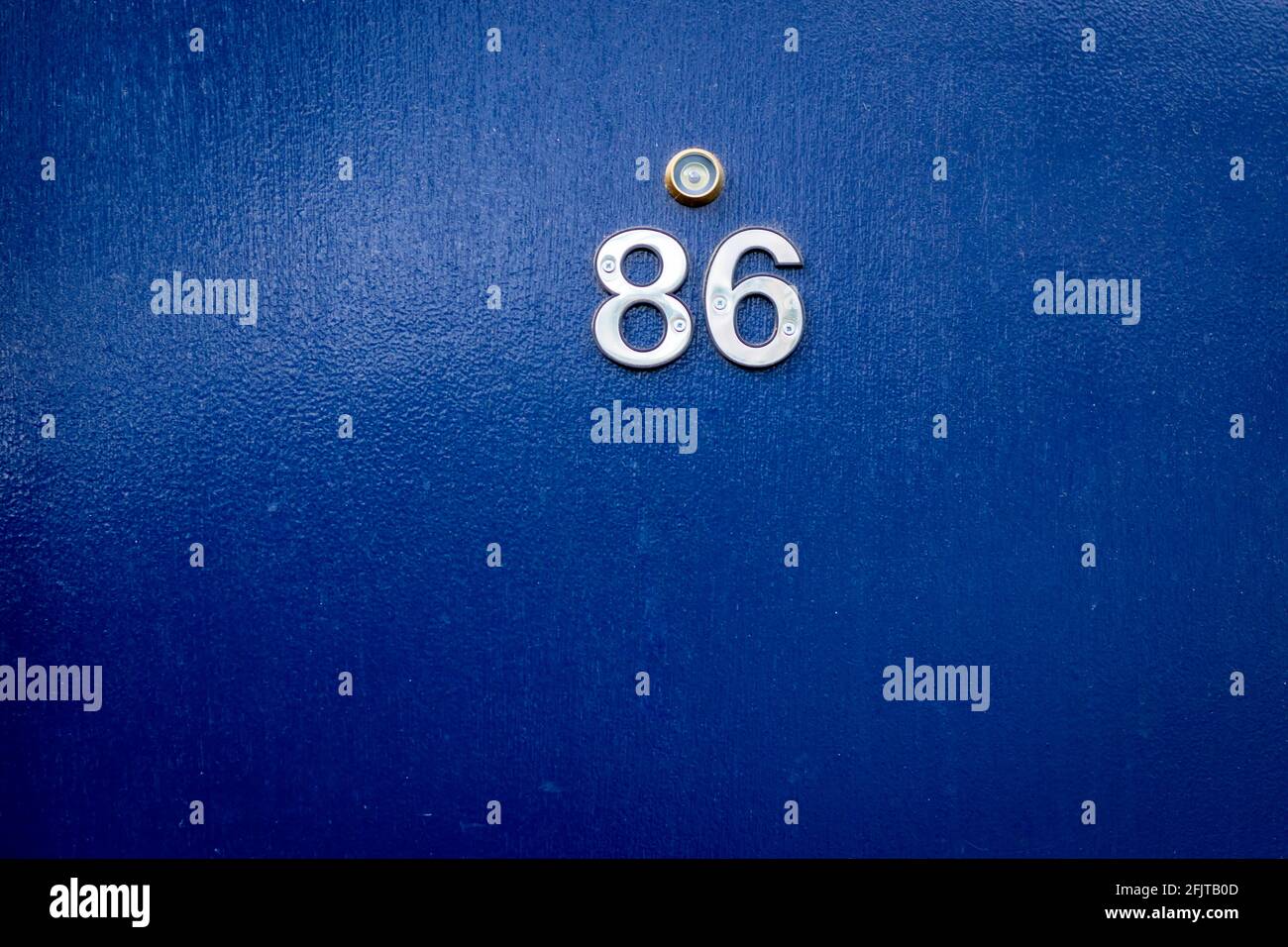 House number 86 in blue with a golden peephole Stock Photo