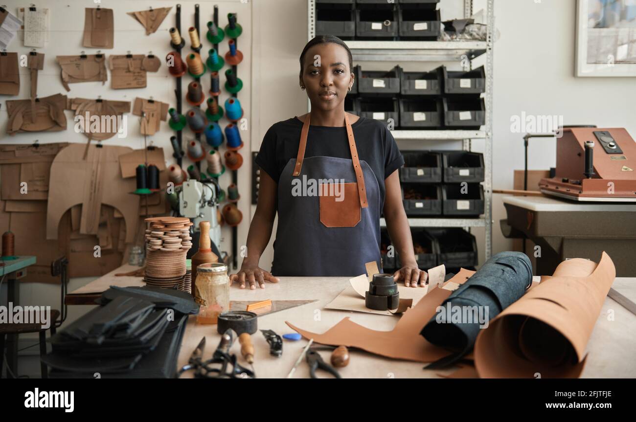 Young African female leather worker standing by a work table Stock Photo