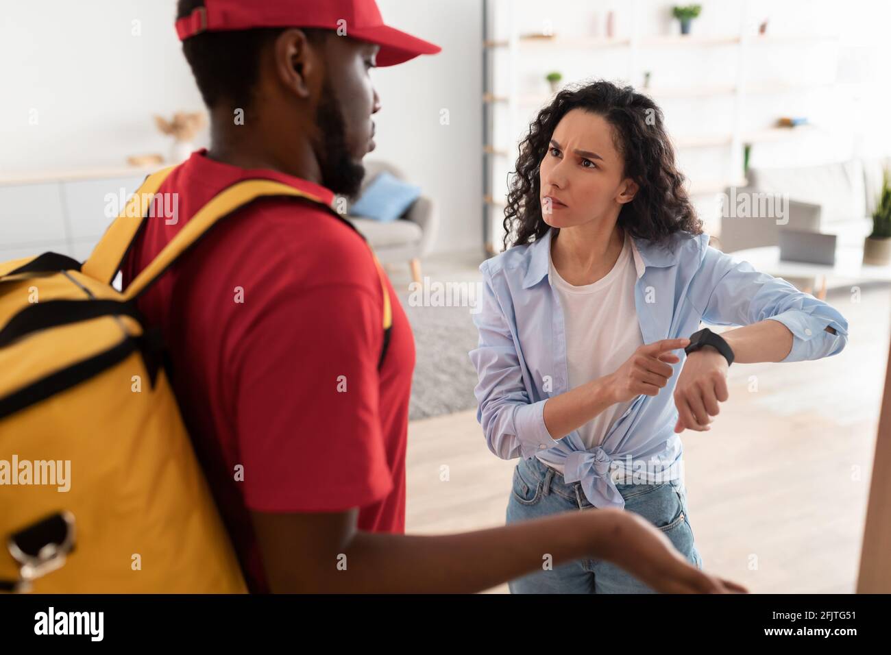 Angry customer pointing at watch, delivery man is late Stock Photo