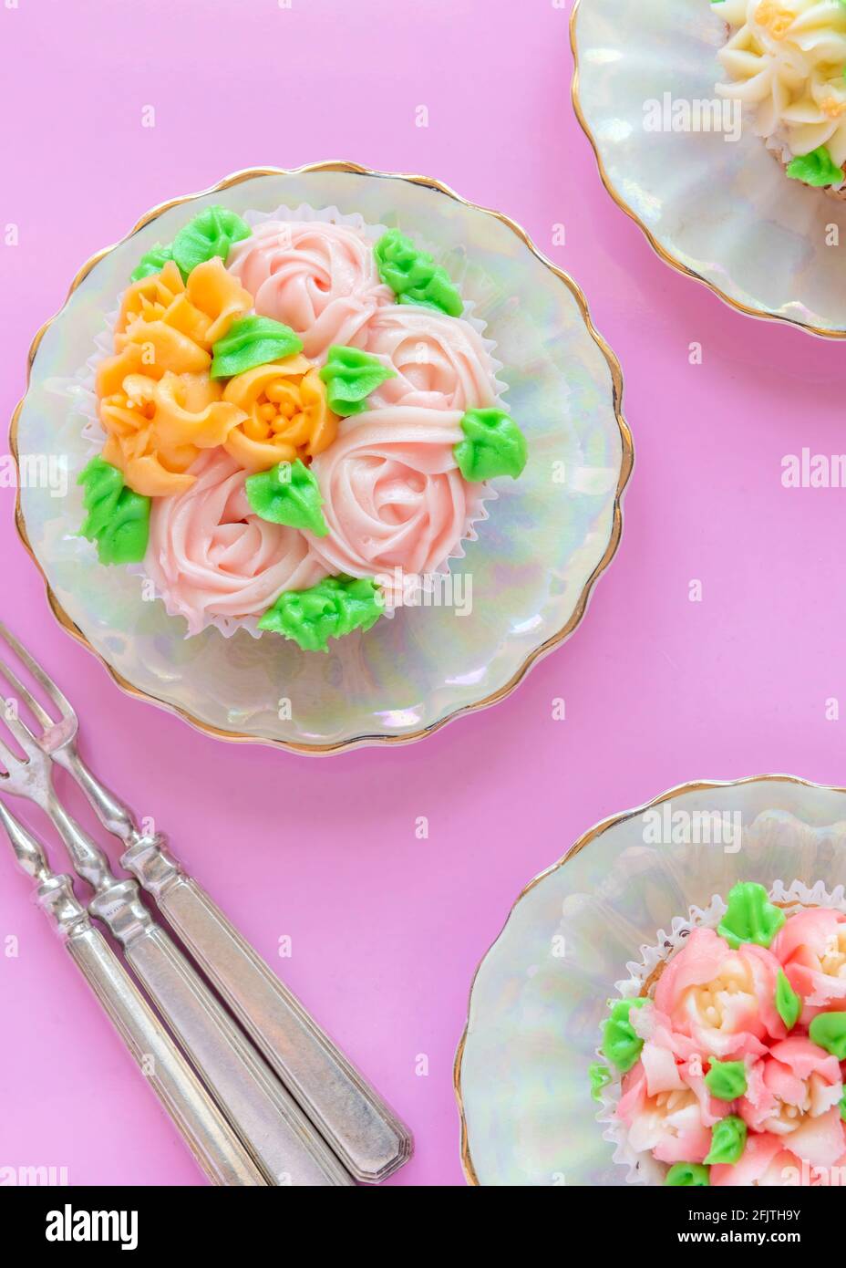 vertical over head image of pretty cup cakes delicately iced with  Russian icing tips pink background with copy space Stock Photo