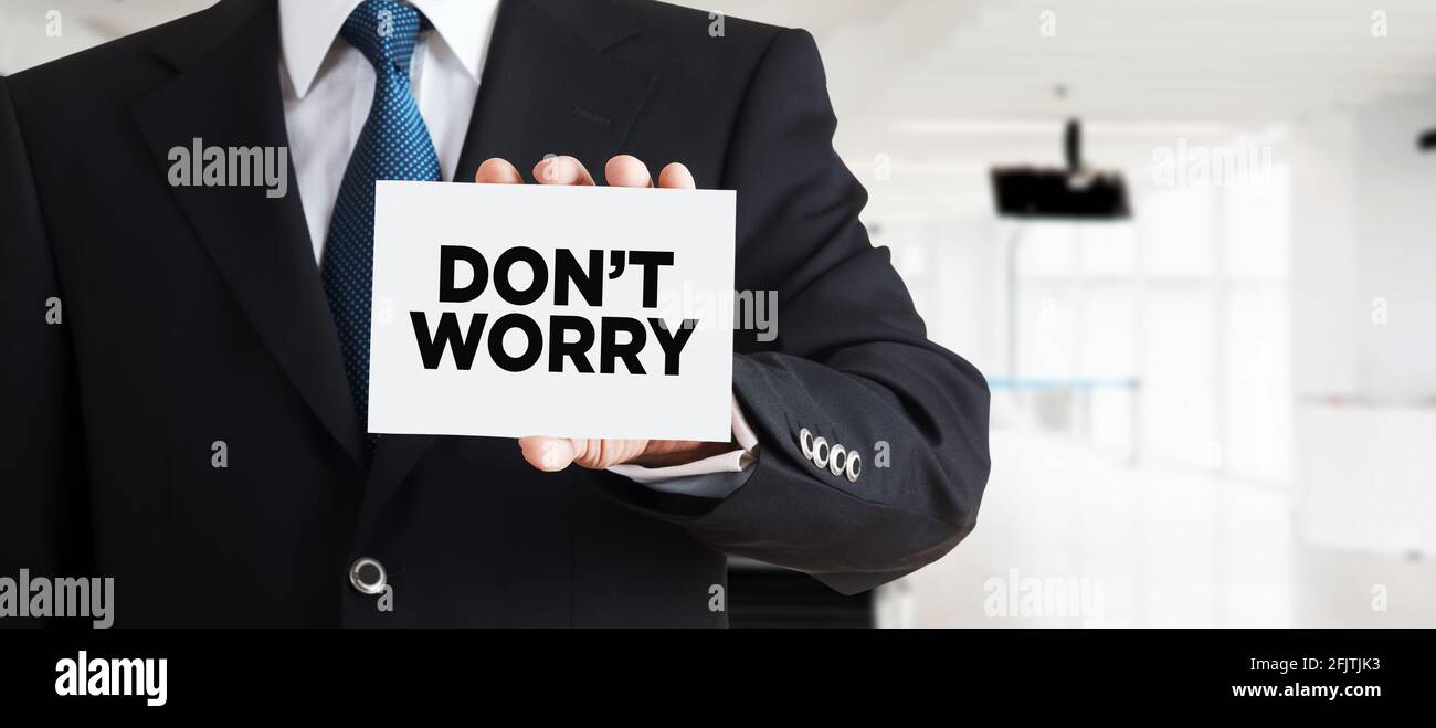Businessman shows a business card with the word don't worry. Overcoming stress and anxiety in business. Stock Photo