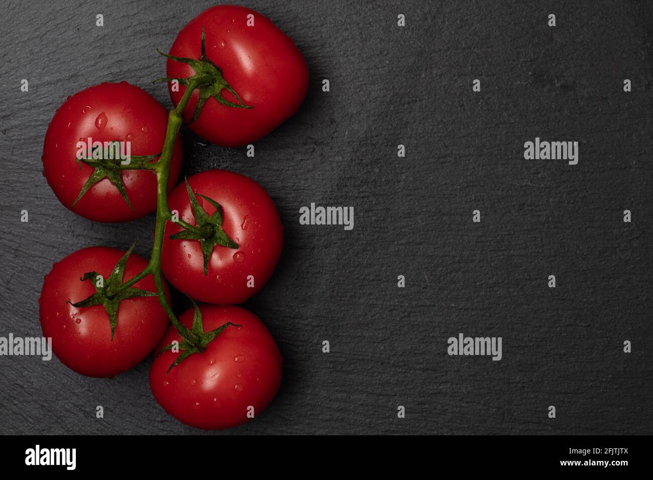 red tomatos on branch on black background Stock Photo - Alamy