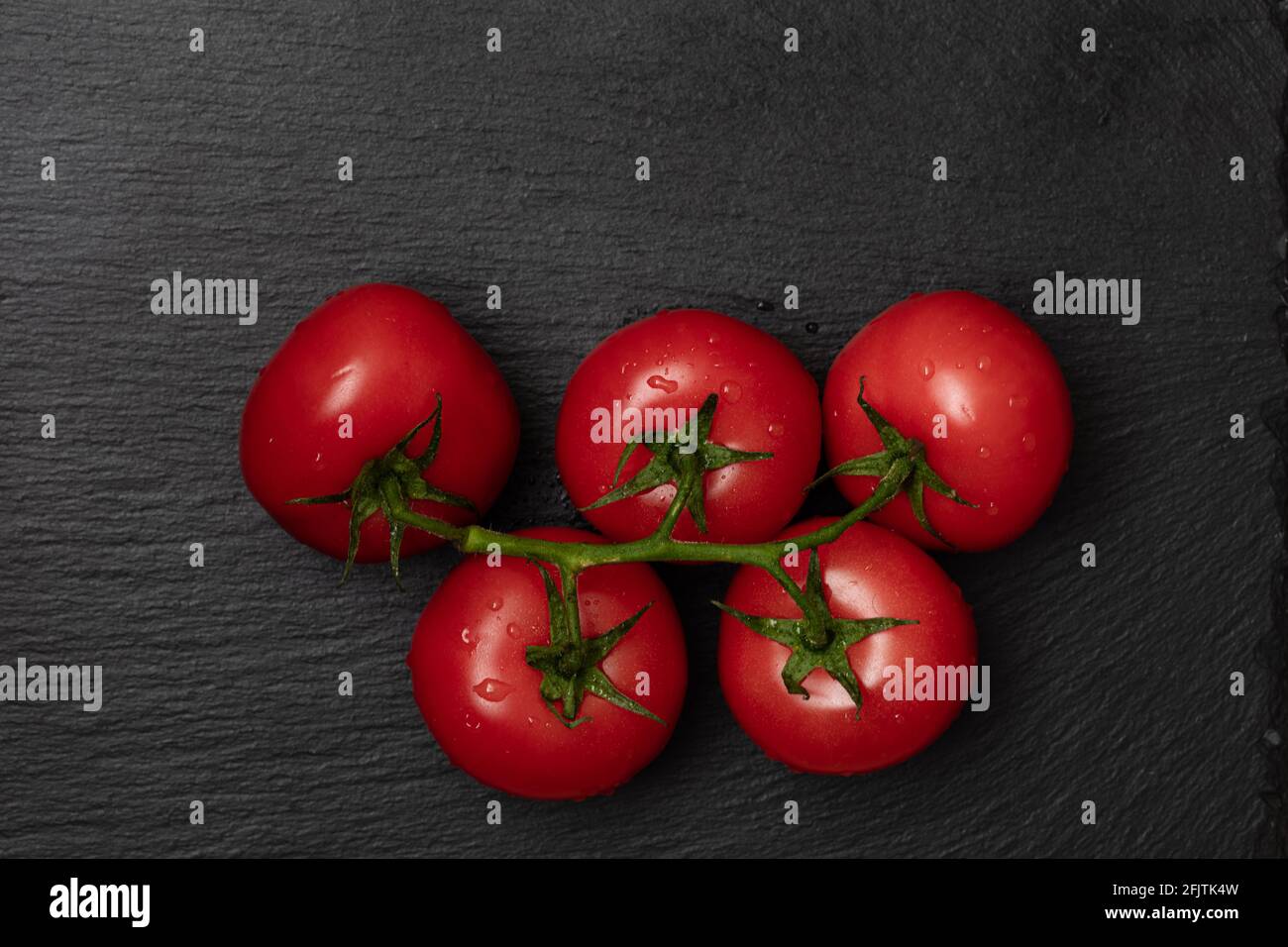red tomatos on branch on black background Stock Photo - Alamy