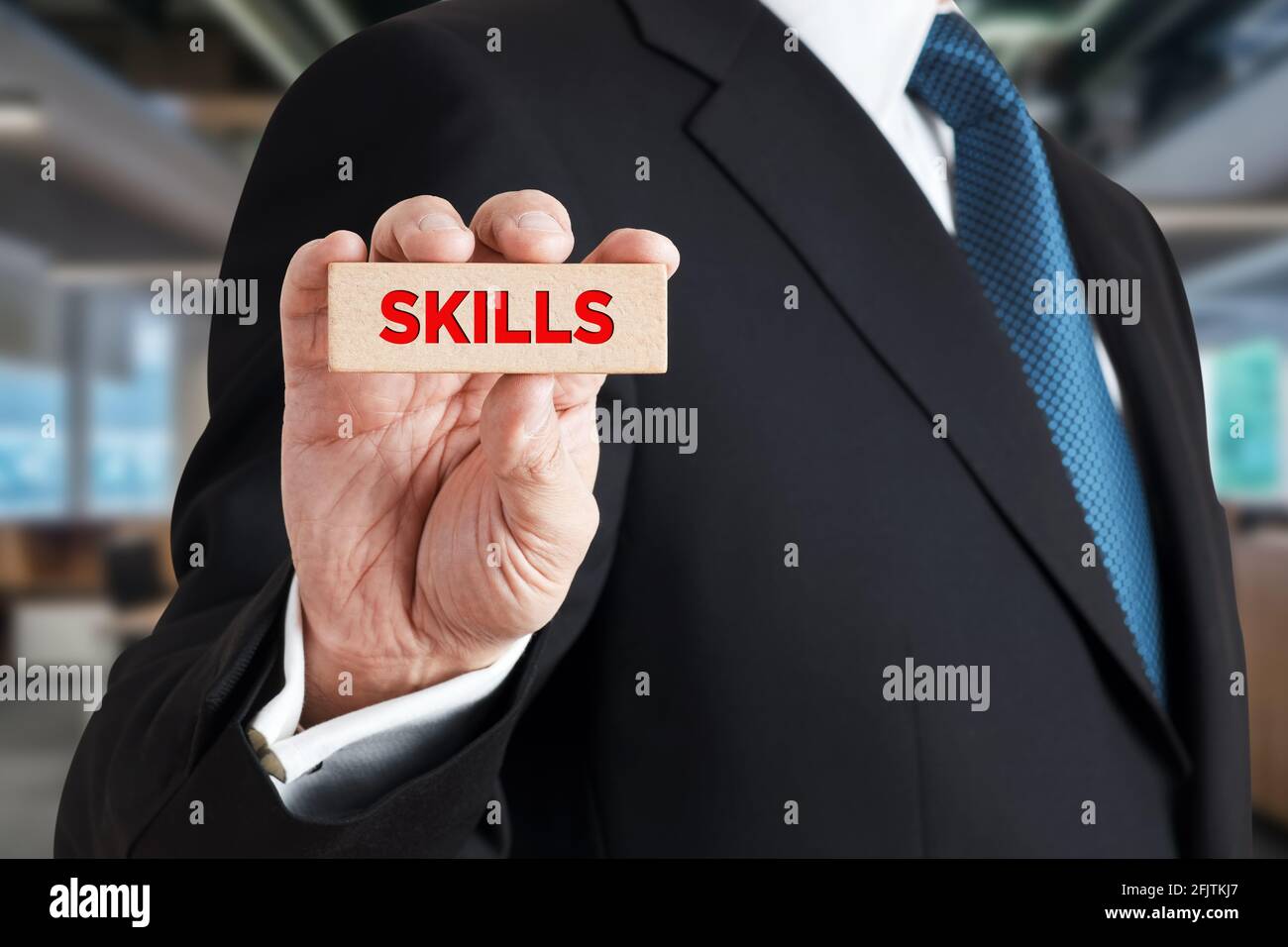 Businessman shows a wooden block with the word skills. Business or job qualification, competence or leadership skills concept. Stock Photo