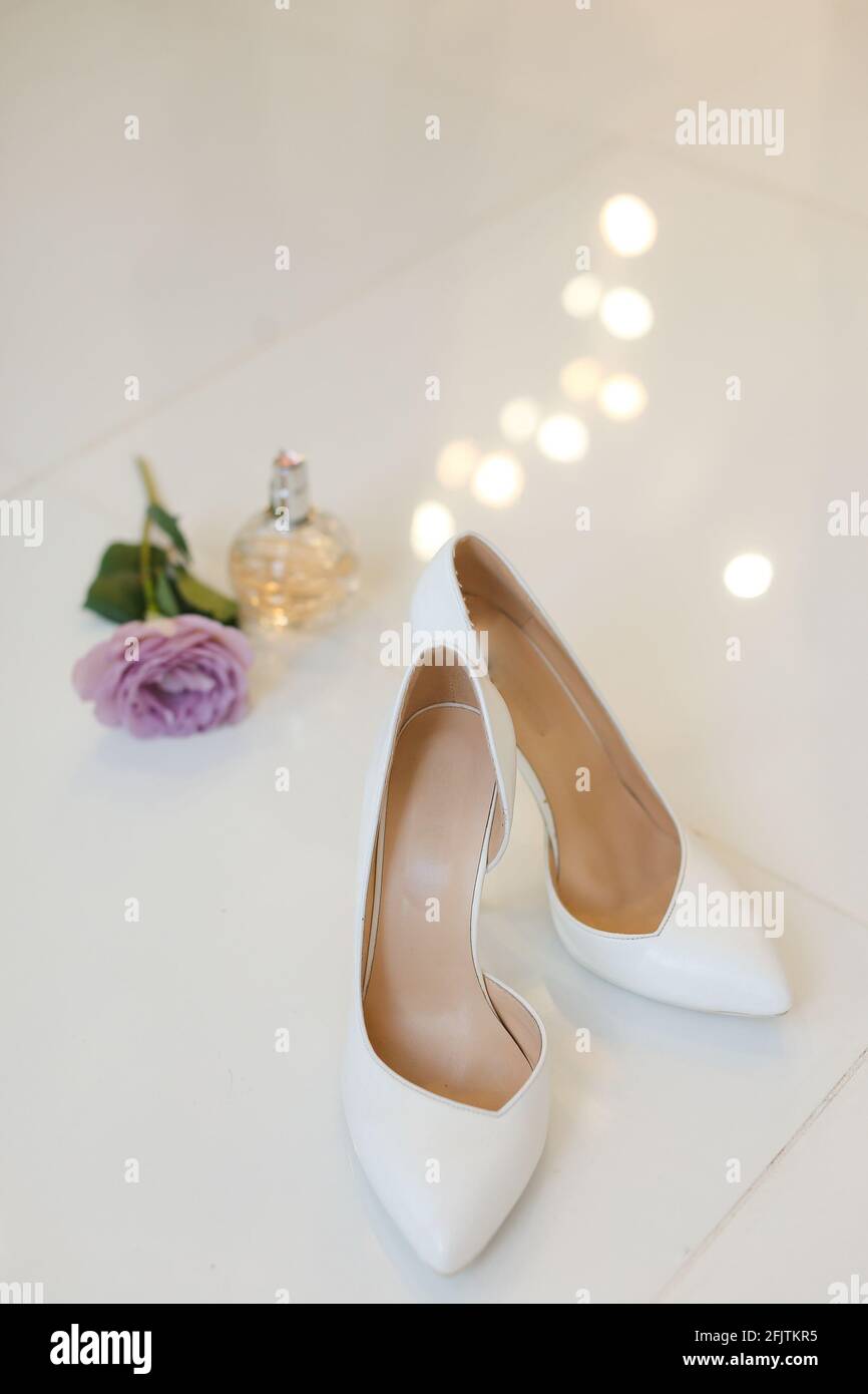 Bridal white shoes with heels near rose and perfumes Stock Photo - Alamy