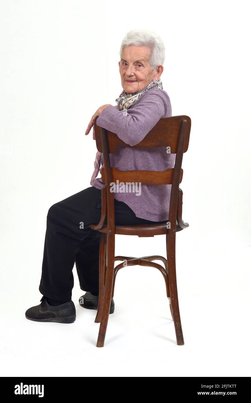 senior woman sitting on chair of profle andlooking at camera on white background Stock Photo