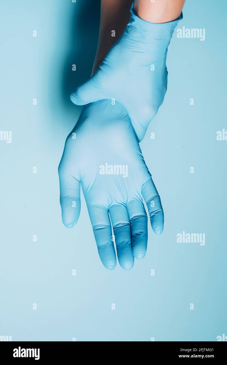 Woman doctor wears medical gloves over blue background. Copy space. National Doctors' Day. International Nurses Day. Health protection equipment Stock Photo