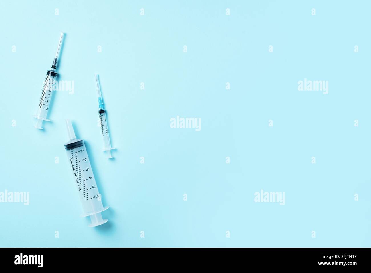 Syringes of different size on blue background. Injections and vaccination concept. Health protection medicine equipment during quarantine Coronavirus Stock Photo