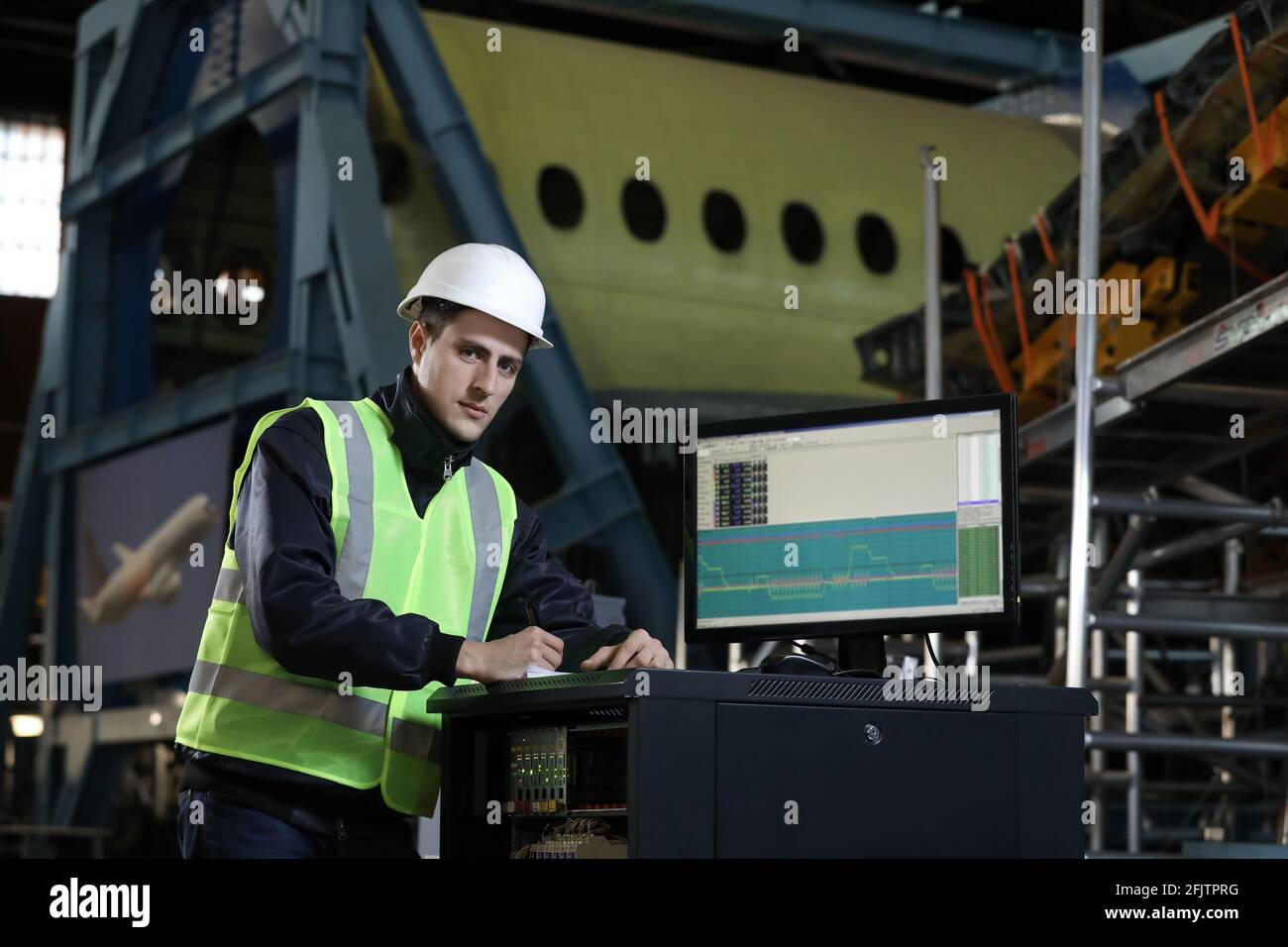 Portrait of a man , factory engineer in work clothes controlling the work process at the airplane manufacturer. Industrial worker. Stock Photo