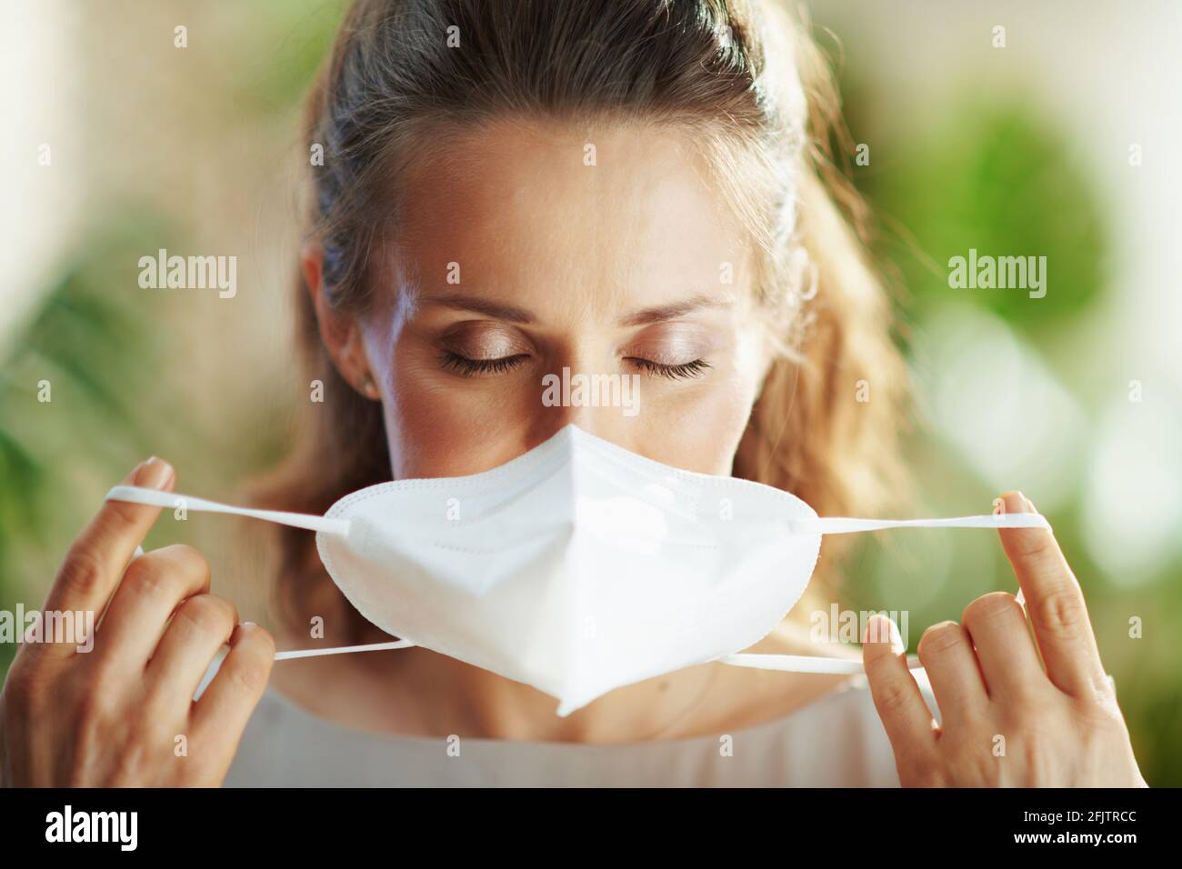 covid-19 pandemic. trendy 40 years old woman in grey blouse wearing ffp2 mask. Stock Photo