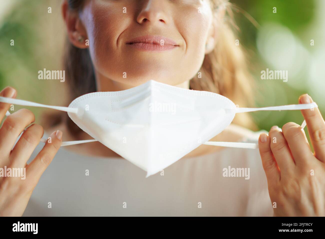 covid-19 pandemic. Closeup on middle aged woman taking off ffp2 mask. Stock Photo