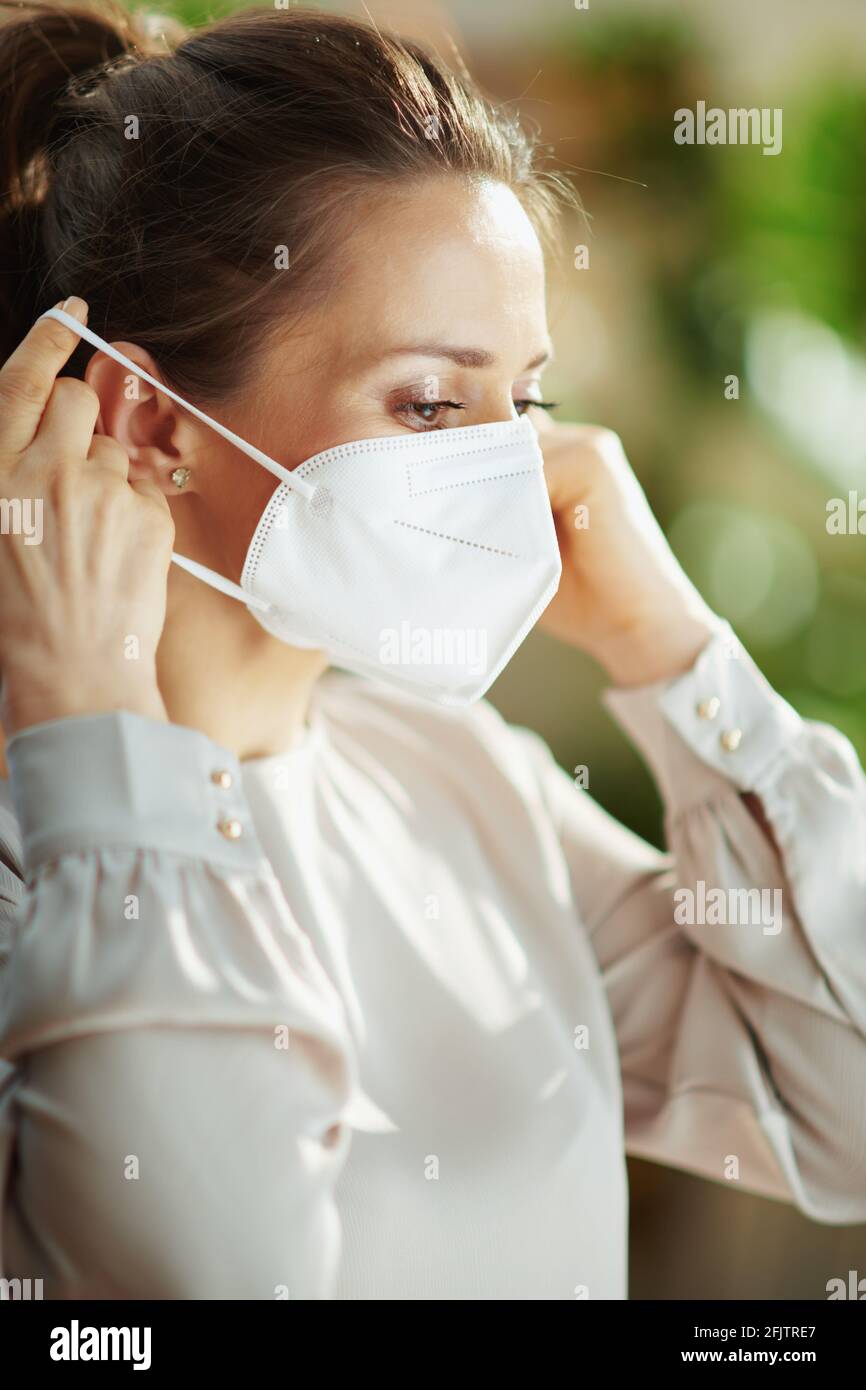 covid-19 pandemic. middle aged woman in grey blouse wearing ffp2 mask. Stock Photo