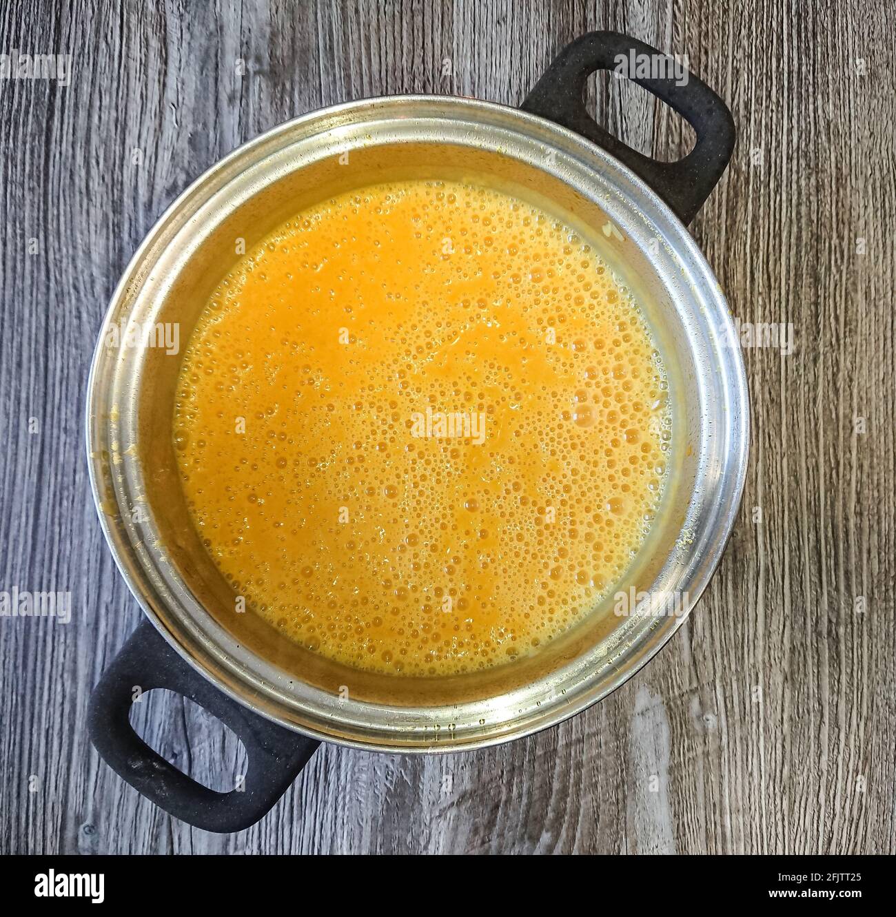 Beautiful colored cream pumpkin soup in pot, close up Stock Photo