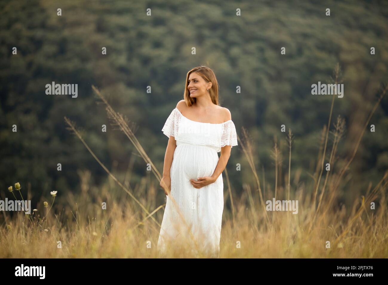 Young pregnant woman in white dress at the summer field Stock Photo - Alamy
