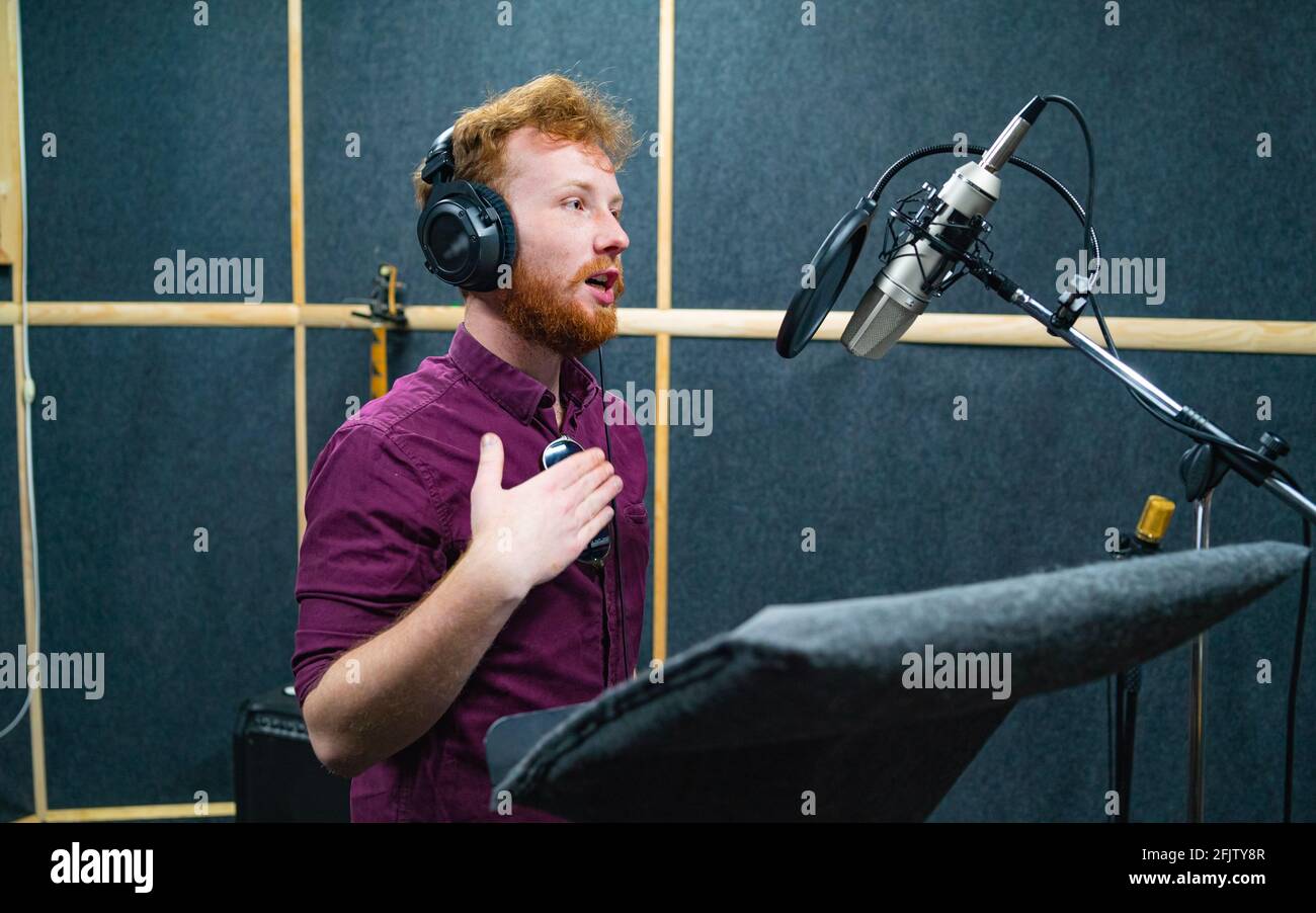 Expressive face of bearded man with red curly hair near microphone Stock Photo