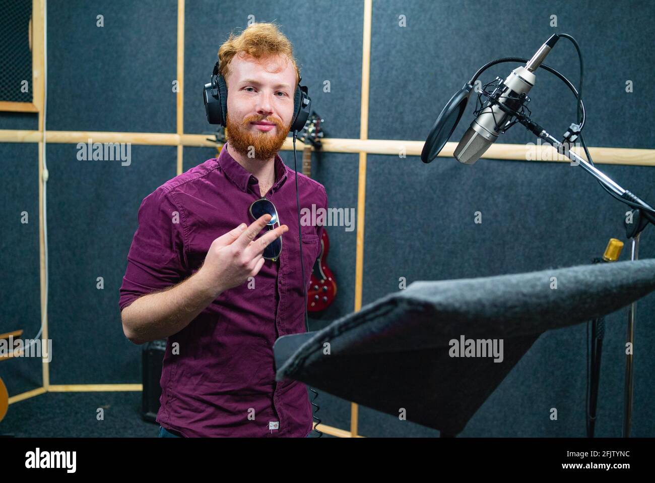 Bearded young man stay near microphone, recording voice in professional studio Stock Photo