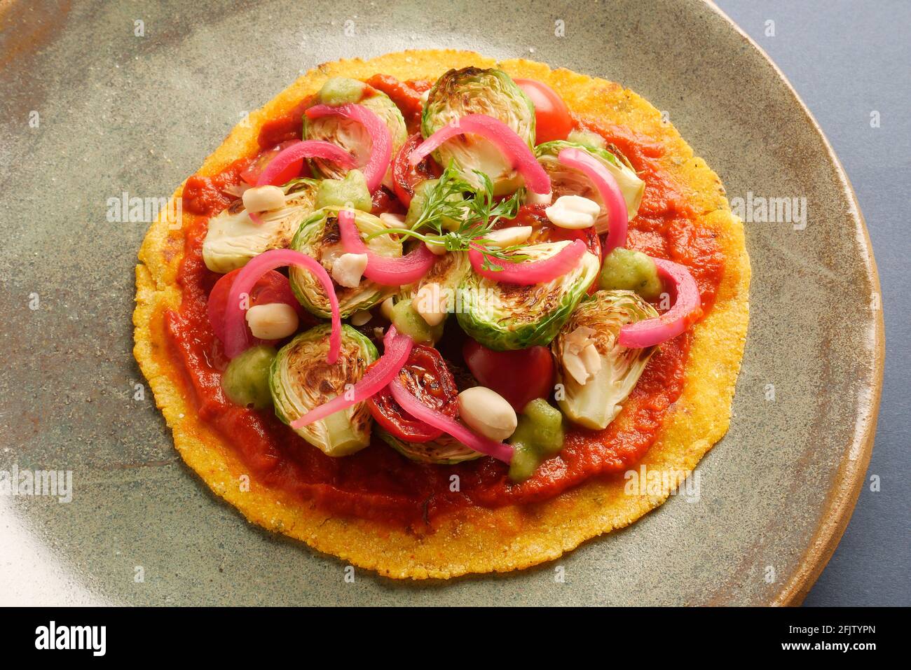 A STILL LIFE OF BRUSSEL SPROUT TACOS,WITH BRUSSEL SPROUTS, CHARRED AND RAW TOMATOES, PICKLED ONIONS, ADOBO SAUCE, SALSA VERDE, PEANUTS,  ON A CORN TOR Stock Photo