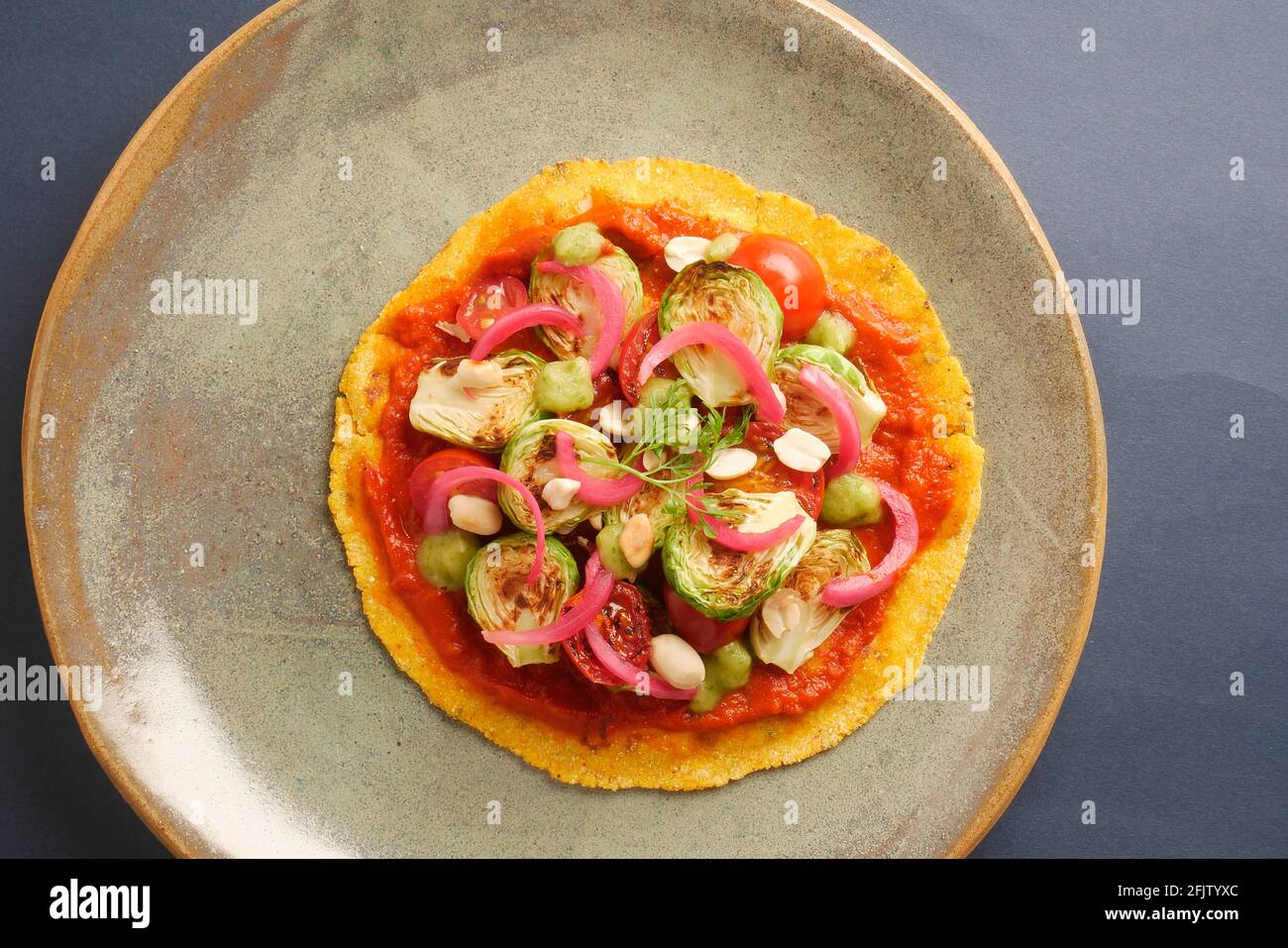 A STILL LIFE OF BRUSSEL SPROUT TACOS,WITH BRUSSEL SPROUTS, CHARRED AND RAW TOMATOES, PICKLED ONIONS, ADOBO SAUCE, SALSA VERDE, PEANUTS,  ON A CORN TOR Stock Photo