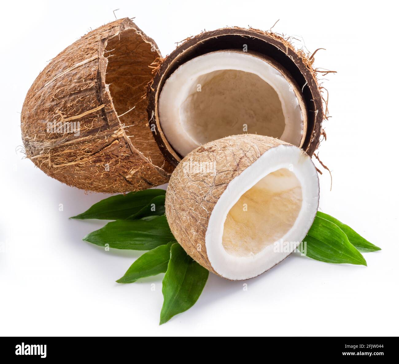 Split coconut fruit over green leaves isolated on white background. Stock Photo