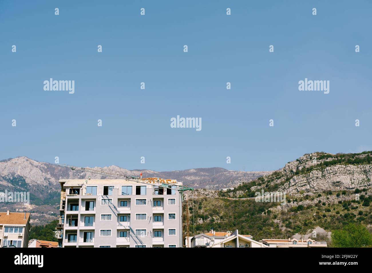 Construction of a residential building against the backdrop of mountains on a bright sunny day Stock Photo