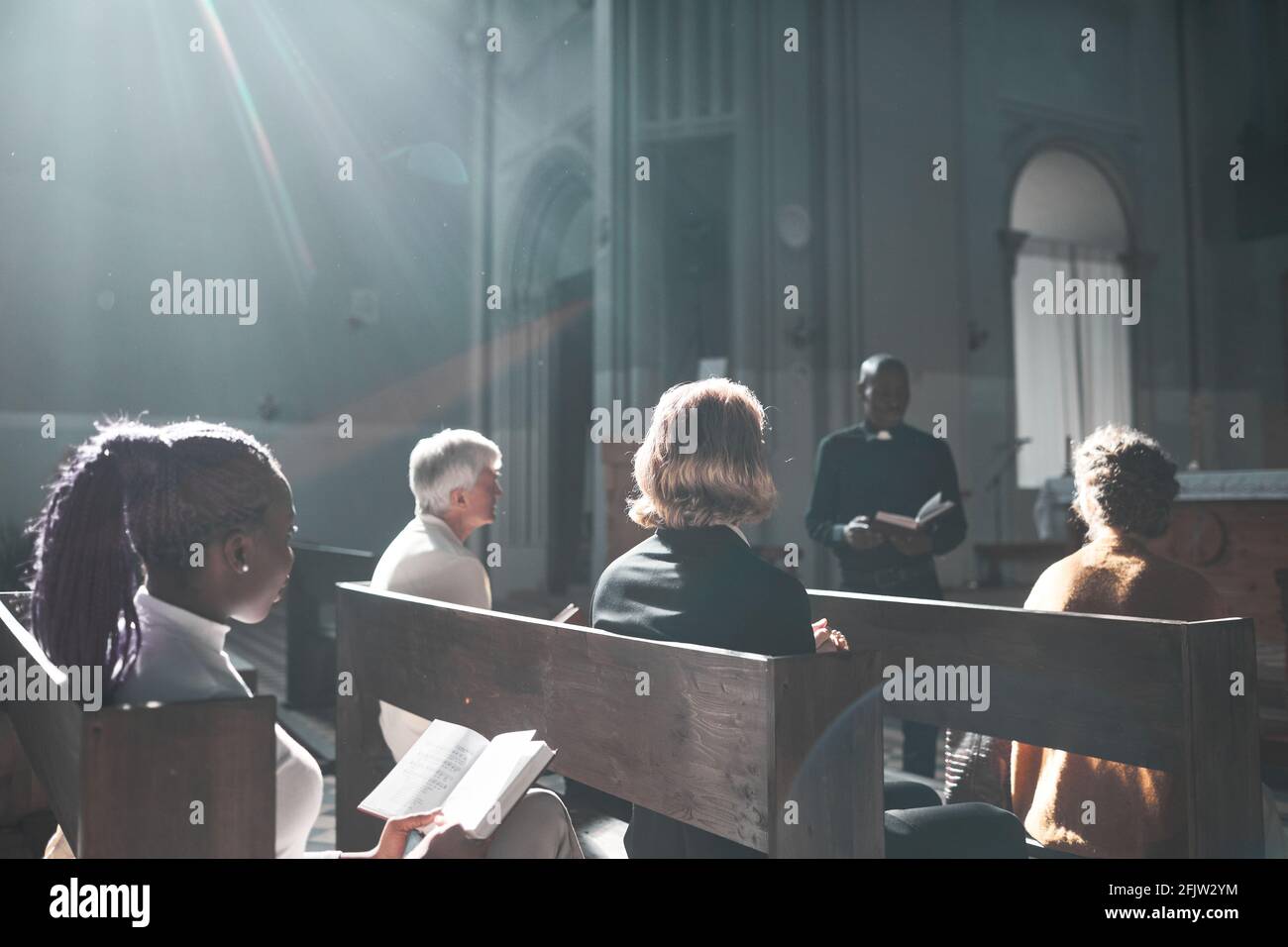 Group of people listening to priest during Sunday mass in the church