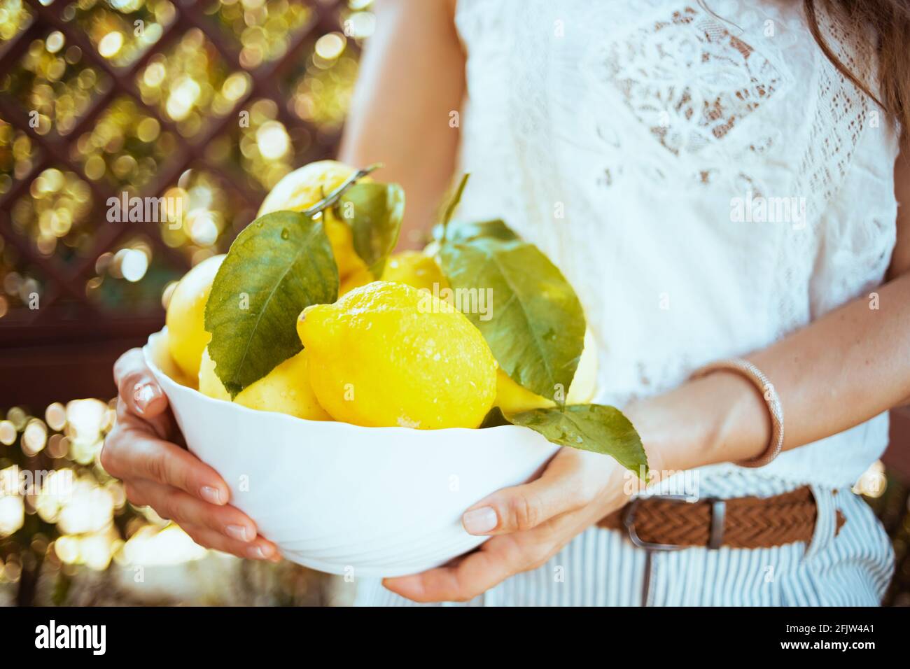 Closeup on woman in white shirt with plate of local farm lemons in the terrace. Stock Photo