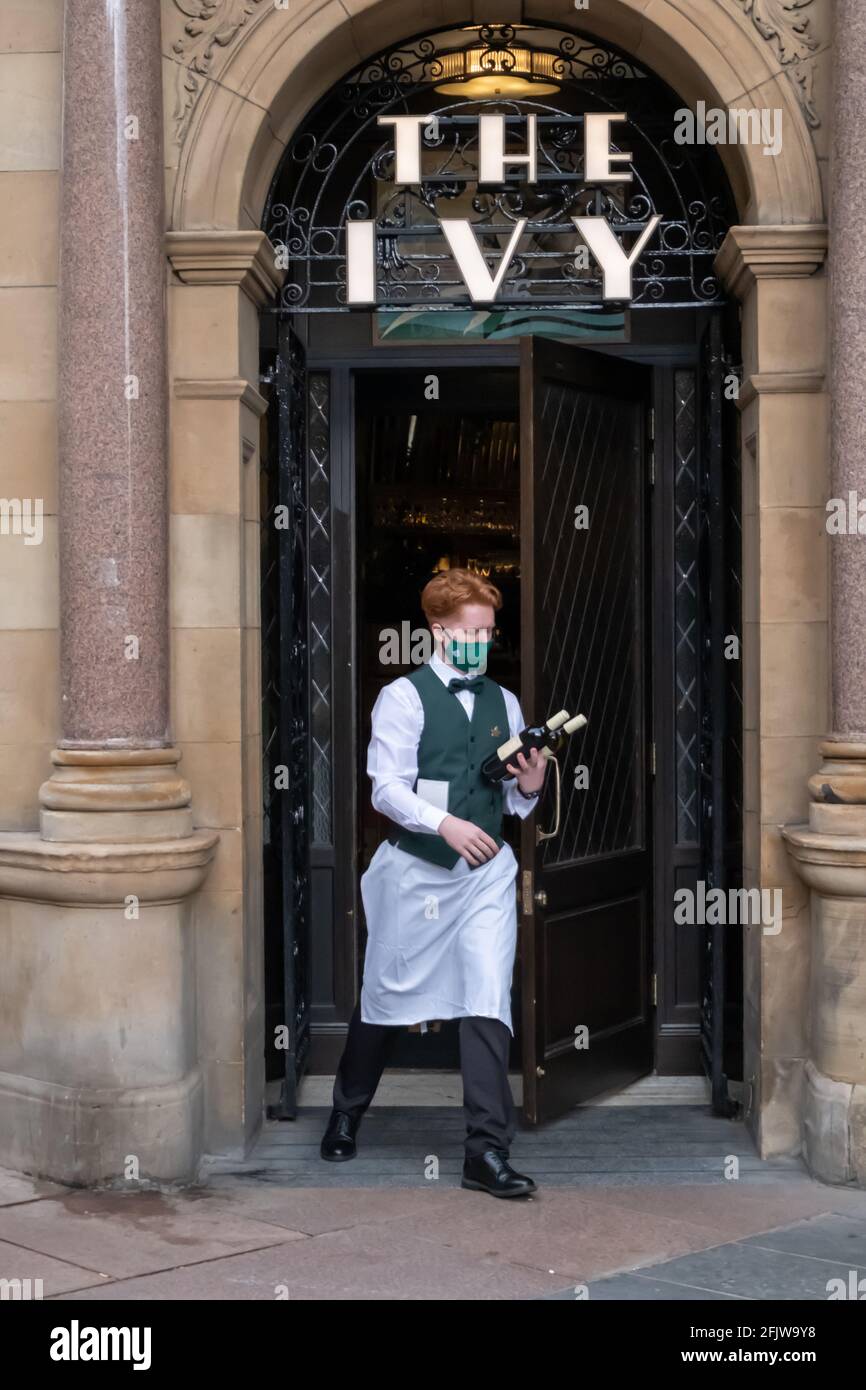 Glasgow, Scotland, UK. 26th April, 2021.  A waiter on duty at The Ivy. The lifting of coronavirus restrictions allows cafes, pubs, restaurants and non essential shops to open across Scotland. Credit: Skully/Alamy Live News Stock Photo