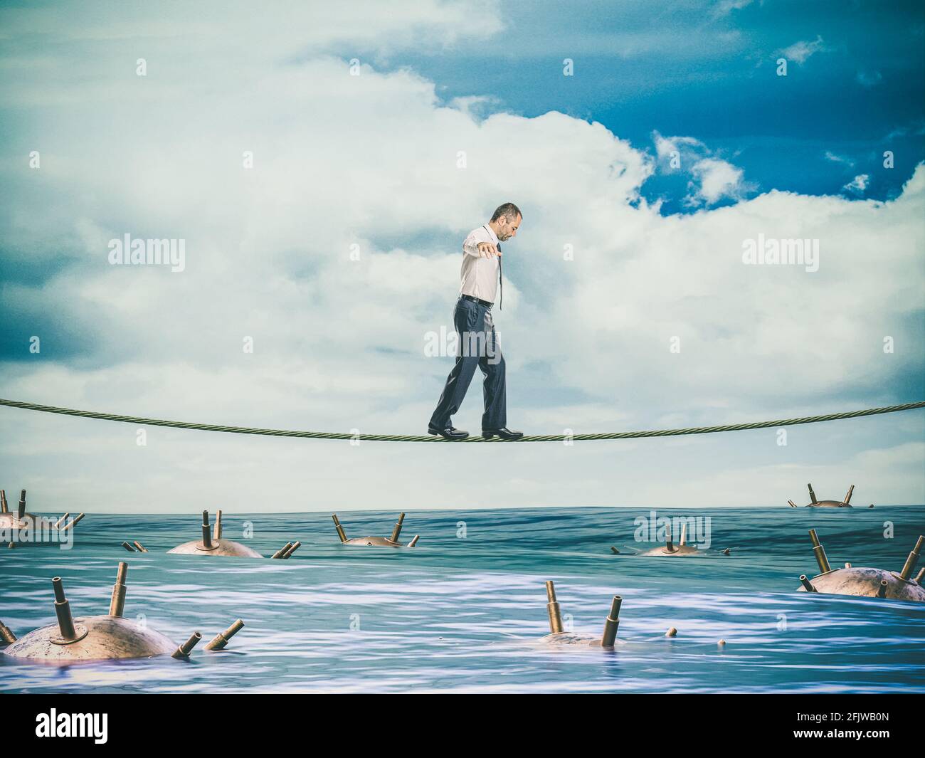 businessman walks on a tightrope over a sea full of mines. concept of risk and danger. Stock Photo