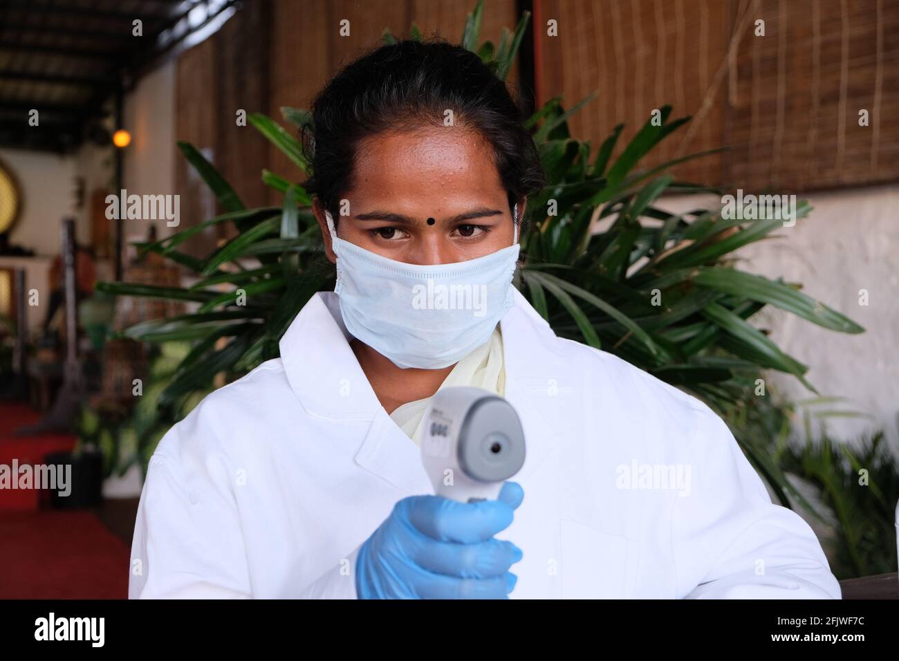 Young Indian female wearing a doctor uniform, gloves and using a ...